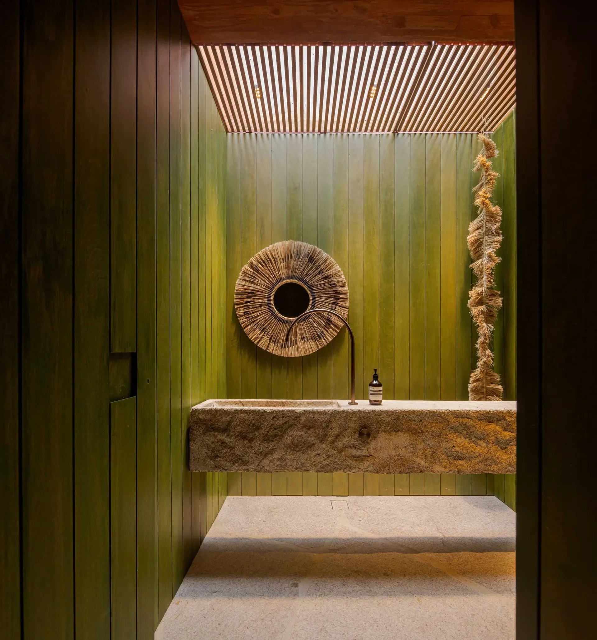 Modern bathroom with a concrete sink and green wooden walls.