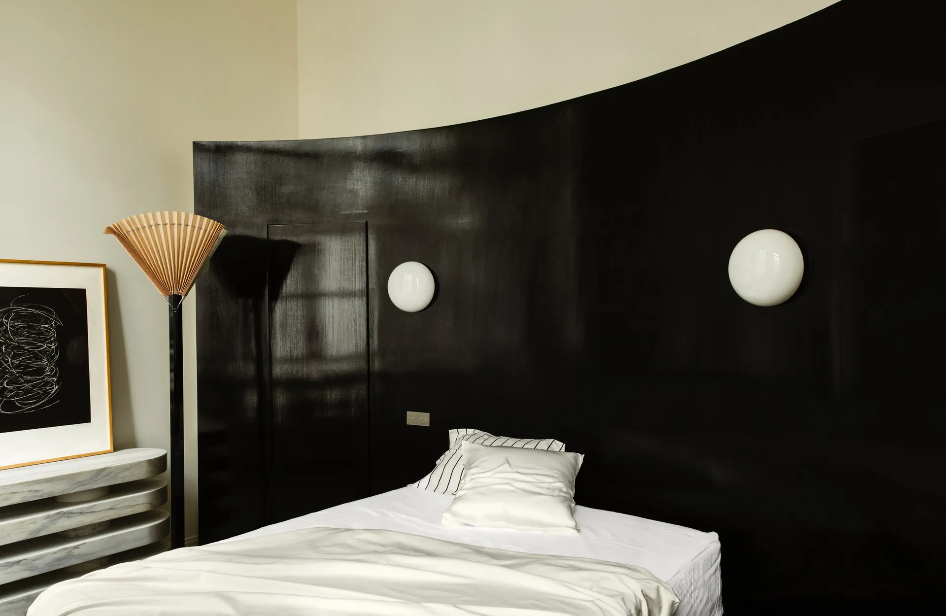 Modern bedroom with black accent wall and white concrete floor and walls