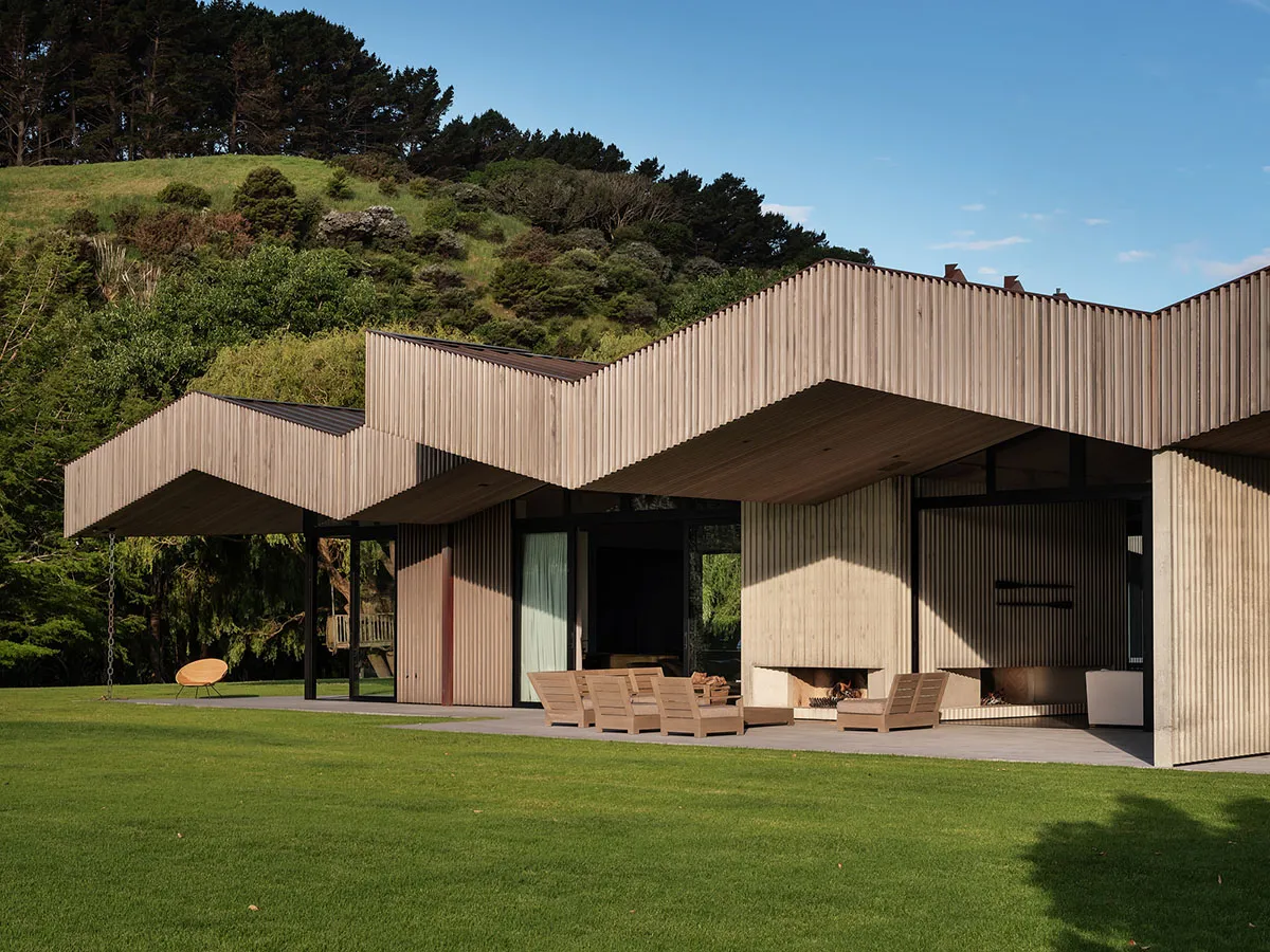 Modern residential exterior featuring curved wooden roof and metal cladding.
