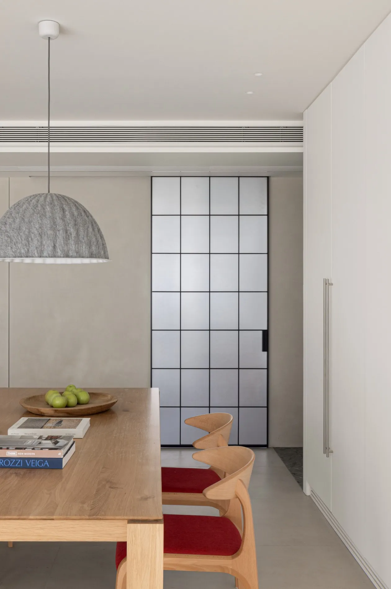 Modern minimalist kitchen features sleek wooden furniture and a geometric glass divider.