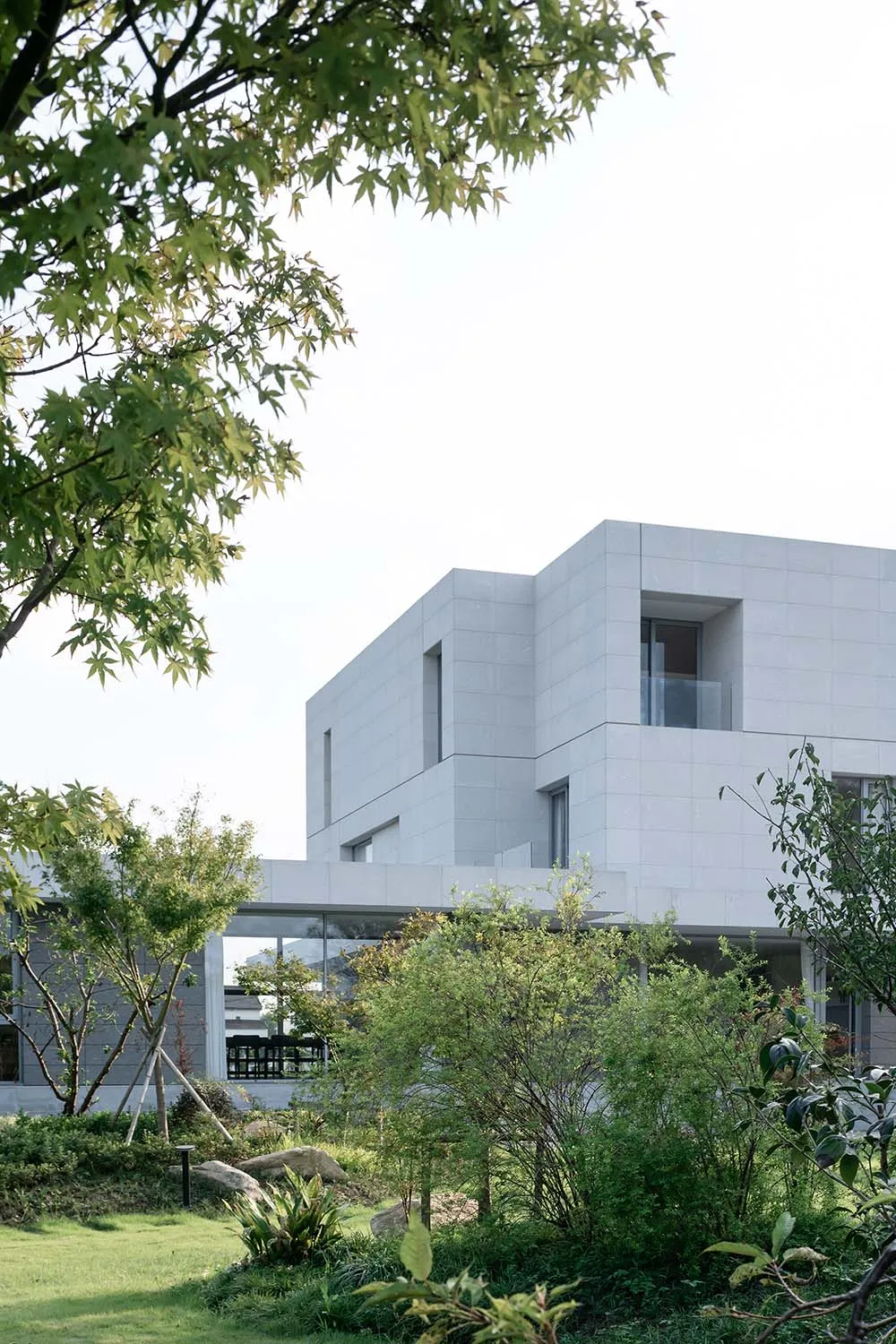 An exterior view of a modern residential house featuring glass and concrete materials.