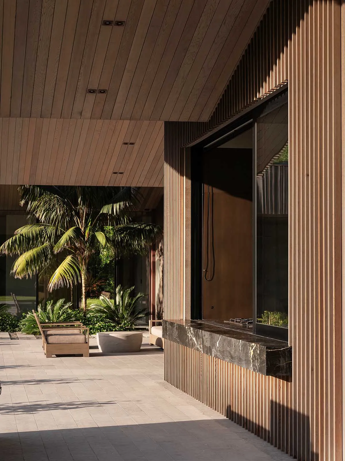 Modern residential patio featuring a wooden ceiling, marble countertop, and metal railings.