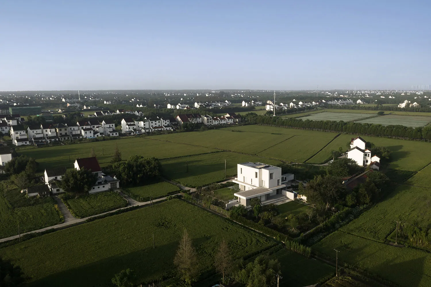 Aerial view of a rural settlement with green fields and white houses.