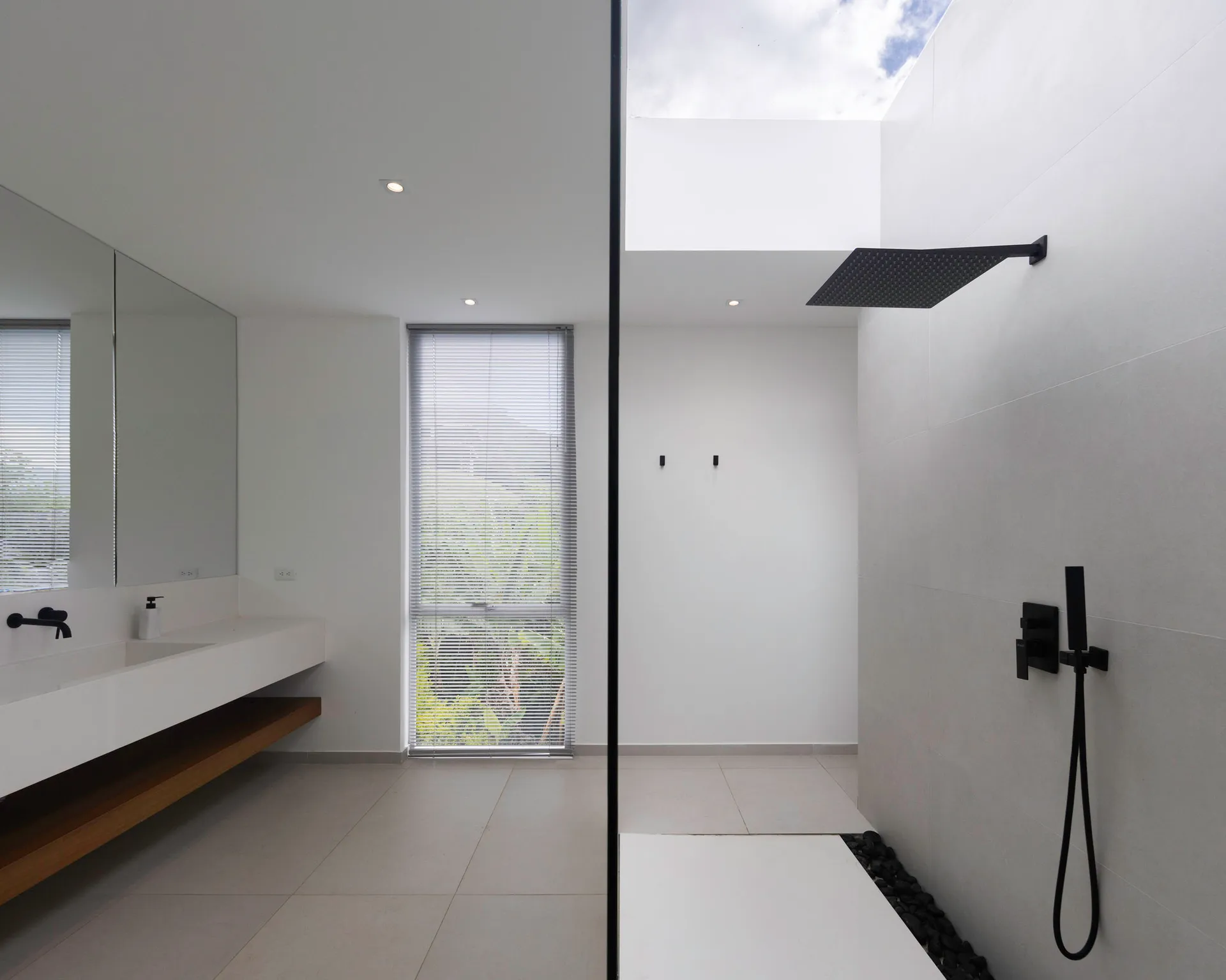 Modern bathroom with concrete walls and floor, minimalist design, and skylight