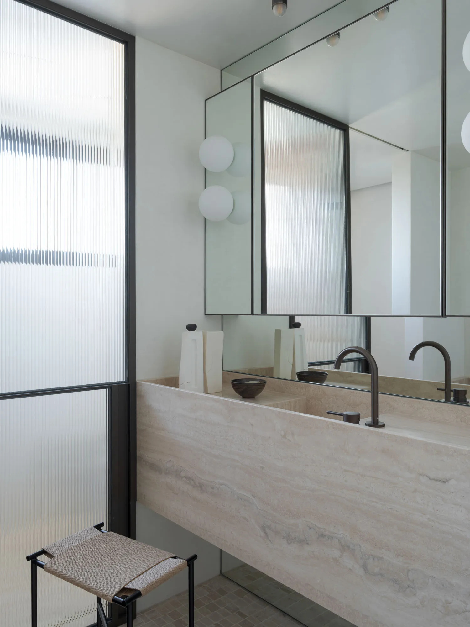 Modern bathroom with stone interior design, featuring a large sink and large mirror.