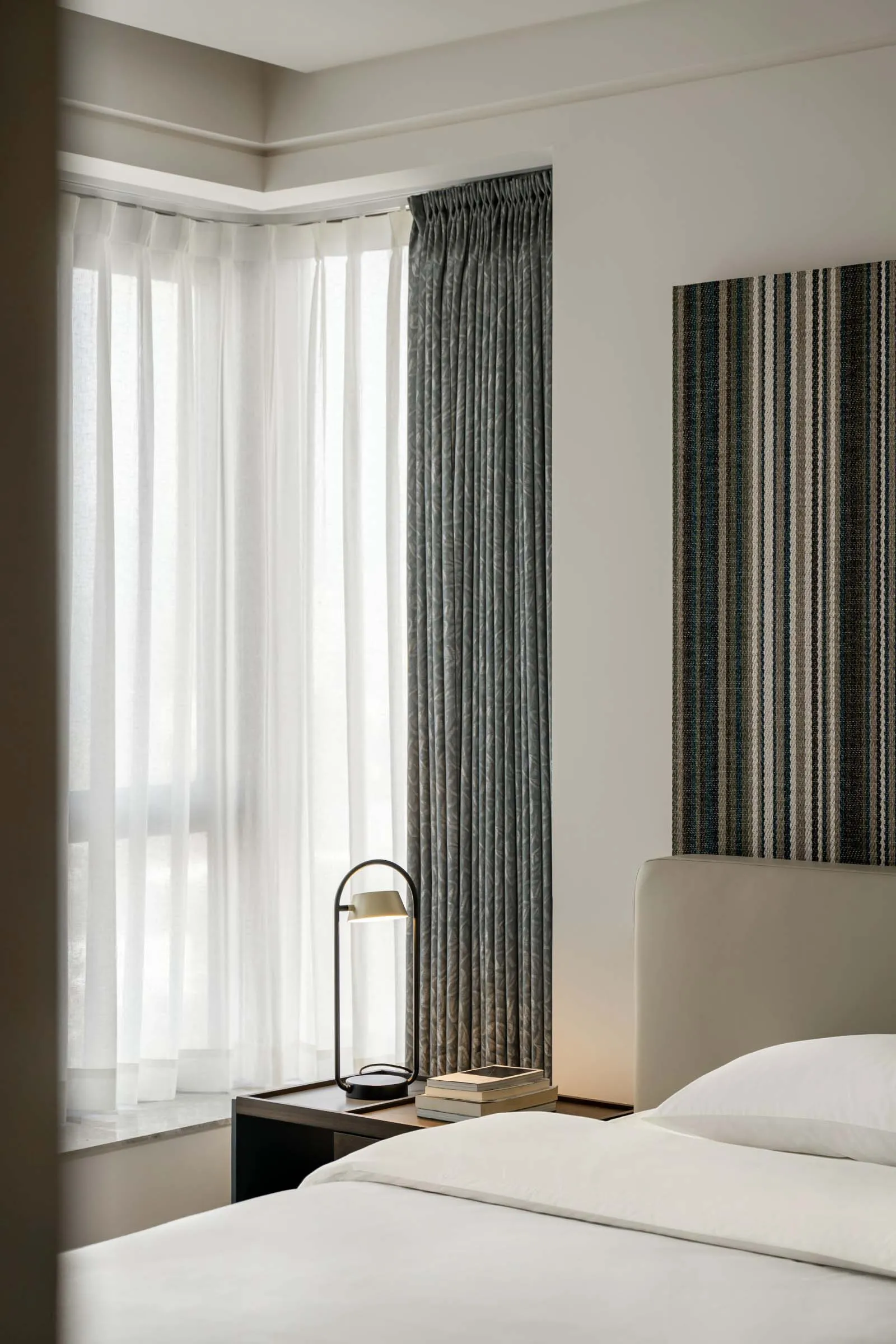 A modern bedroom featuring grey and white fabric curtains