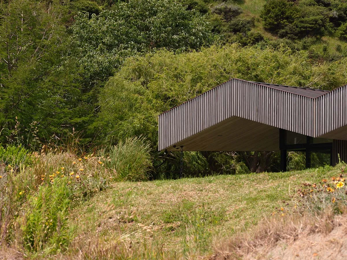 A modern building with a metallic exterior surrounded by greenery.
