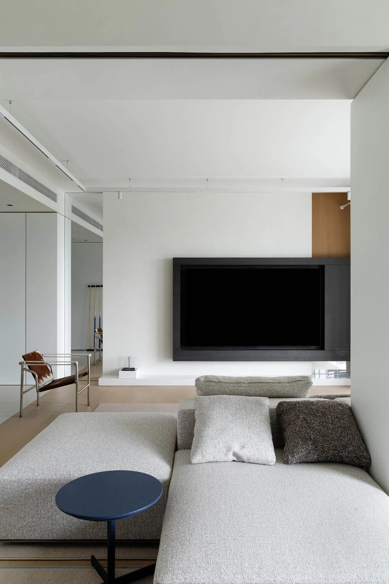 Modern minimalist living room with grey fabric sofa, black coffee table, and black TV on the wall.