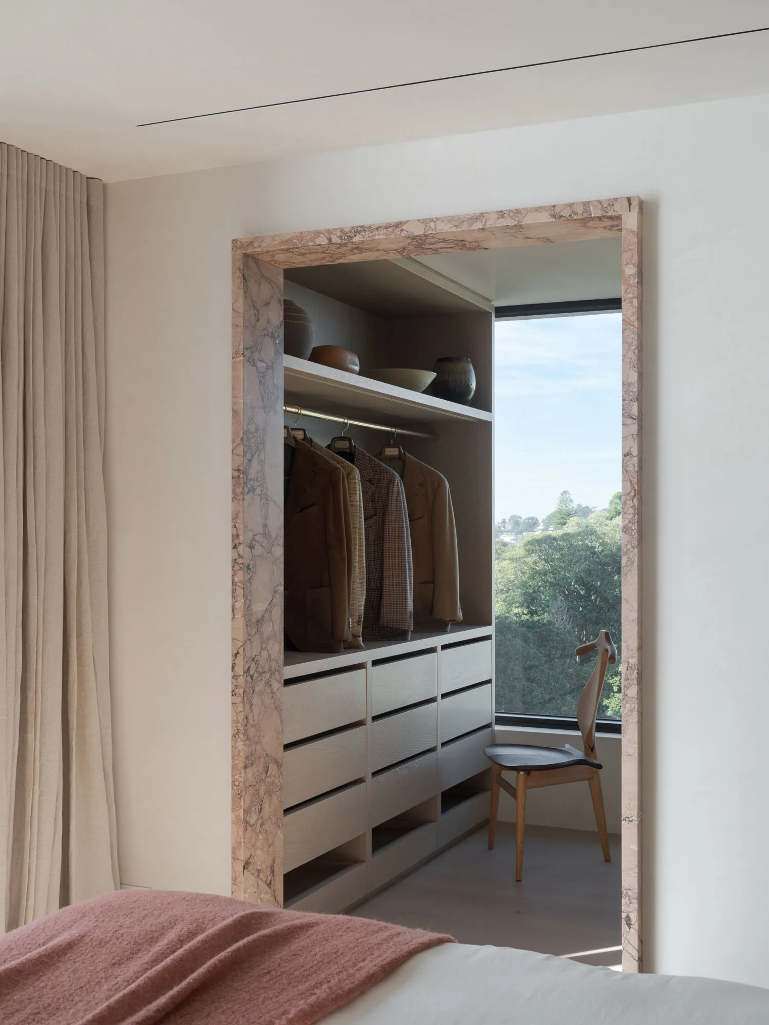 Modern wardrobe with marble and wooden elements, featuring a view of greenery.