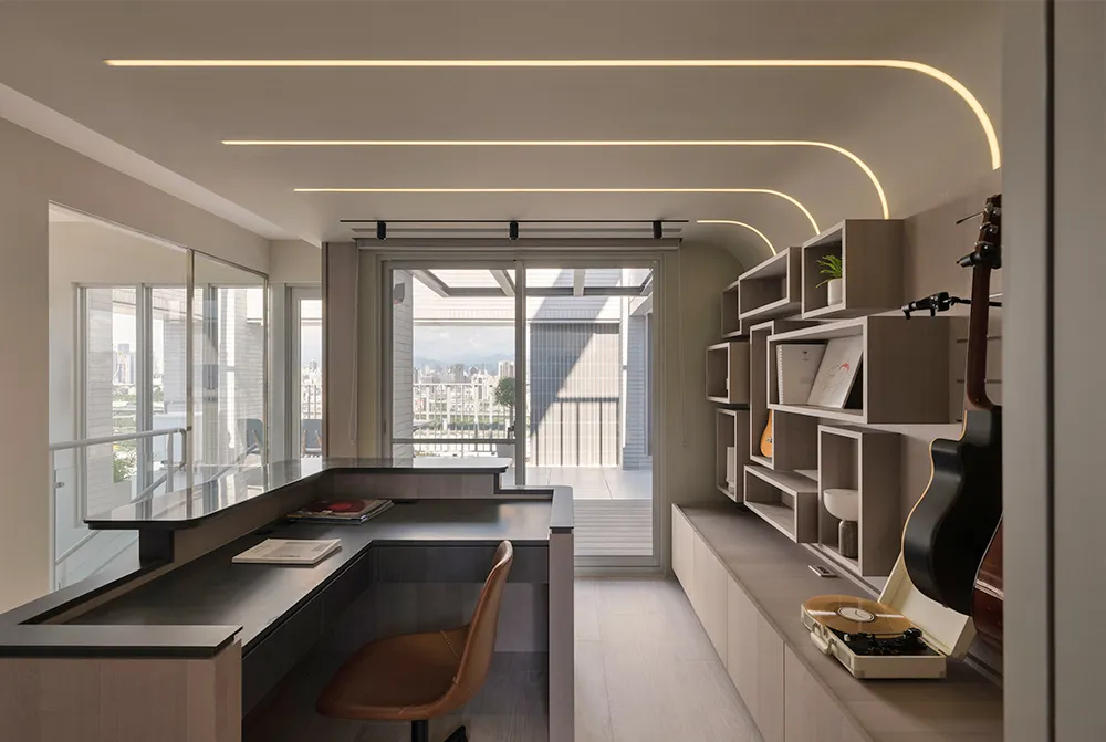 A modern home office featuring a bookshelf with a variety of items, including books, a guitar, and a vinyl record player.