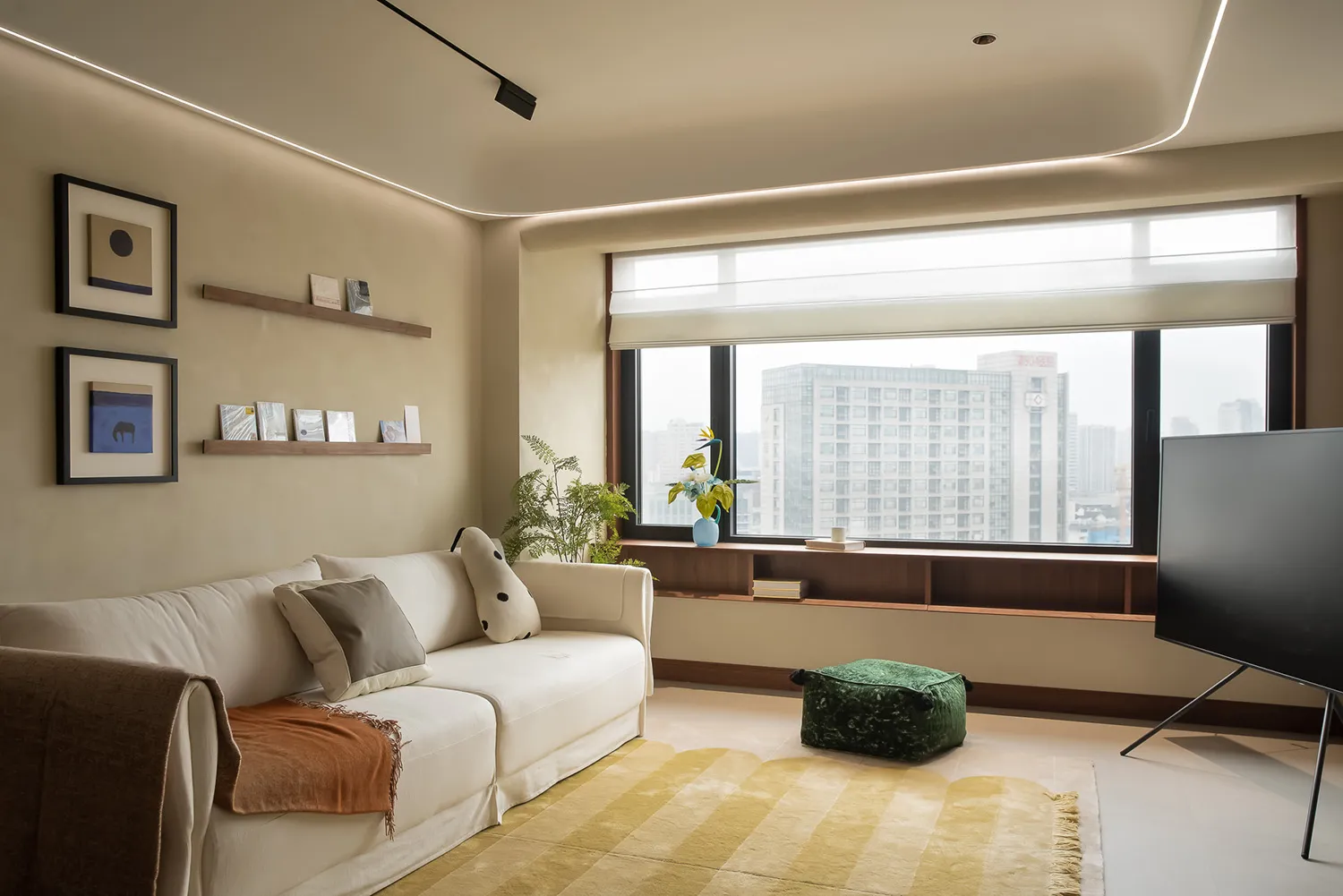 Modern living room with white sofa, green pouf, and yellow rug overlooking cityscape.