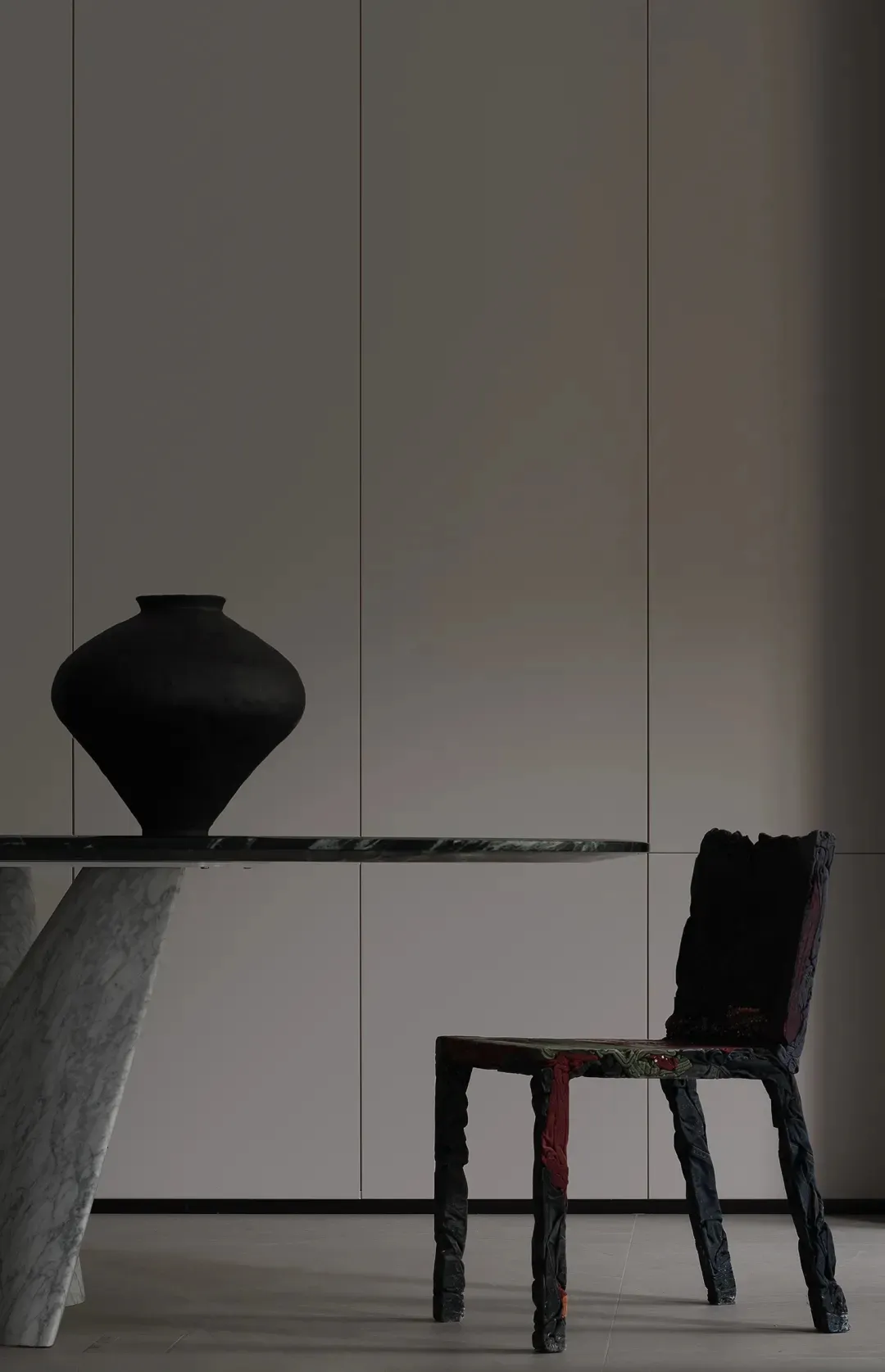 Modern dining room featuring a marble table with a black vase and a uniquely textured wooden chair.