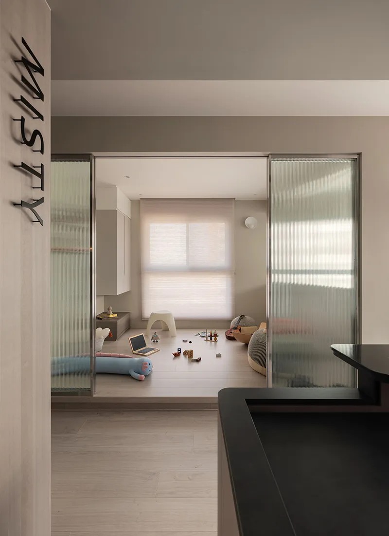A modern residential playroom featuring wooden flooring, steel furniture, and glass doors.