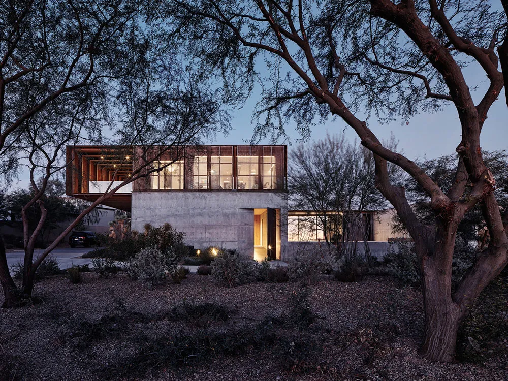 A modern residential architecture featuring a combination of concrete and wood materials with a glass facade.