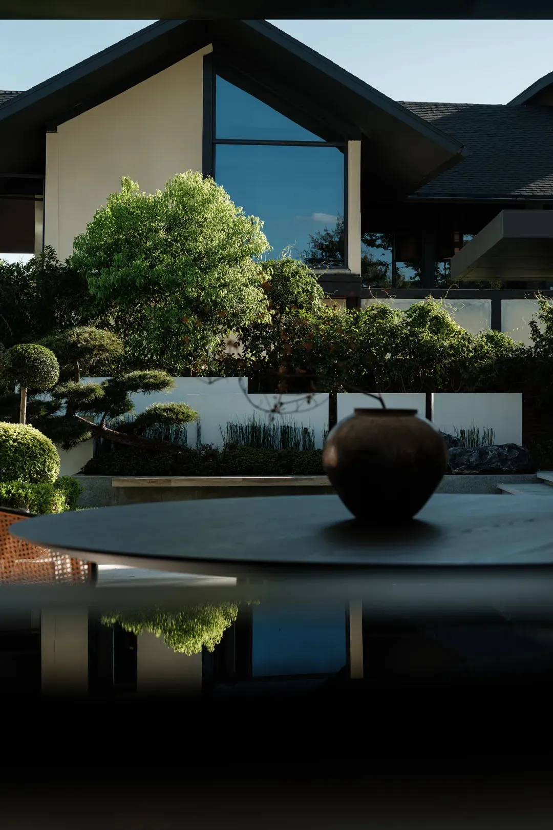 A modern residential exterior featuring large glass windows, stone accents, and wooden elements.