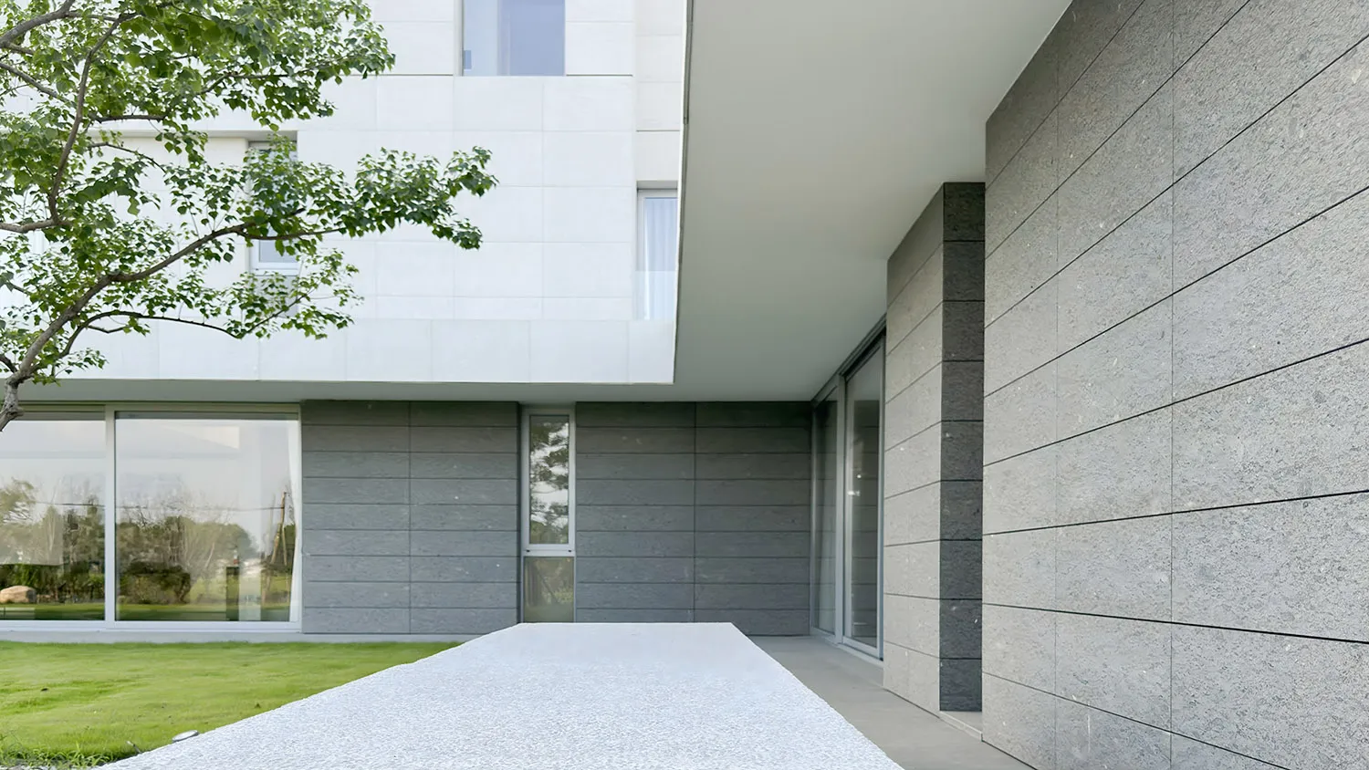 A modern minimalist entryway with a concrete wall and large windows.