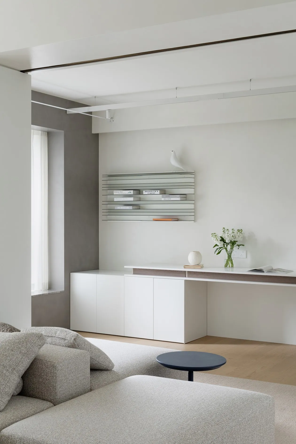 A modern minimalist living room with white furniture and white shelves.