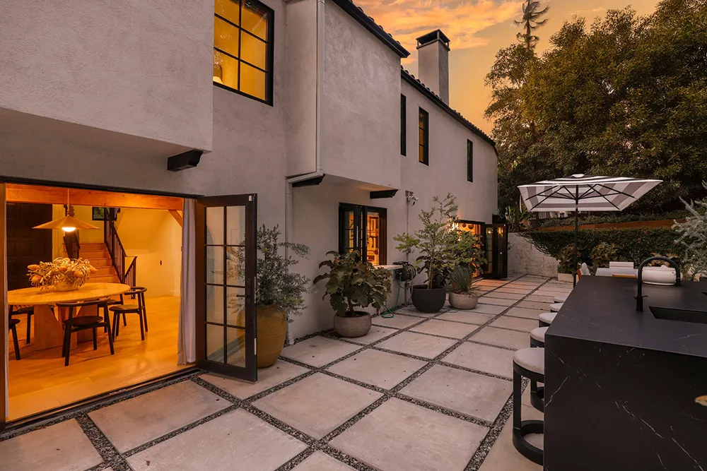 An inviting outdoor space with concrete pavers, a wooden dining table, and a cozy patio setting.