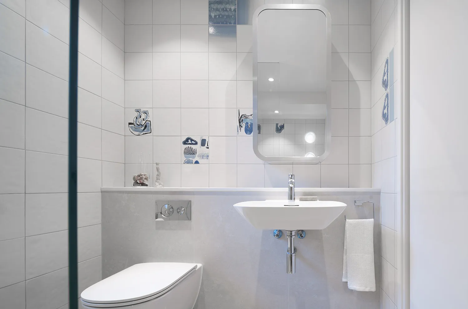 Modern minimalist bathroom with white tiles and fixtures.