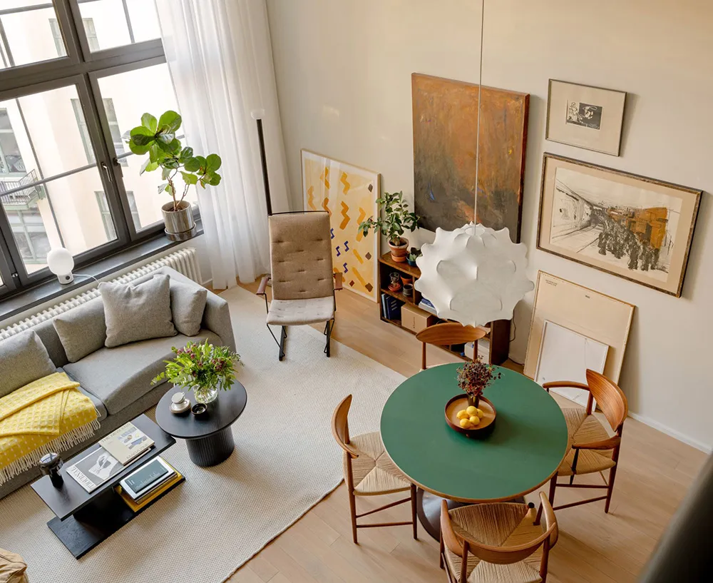 A minimalist living room with mixed materials, featuring a circular table, wooden chairs, and modern furniture.