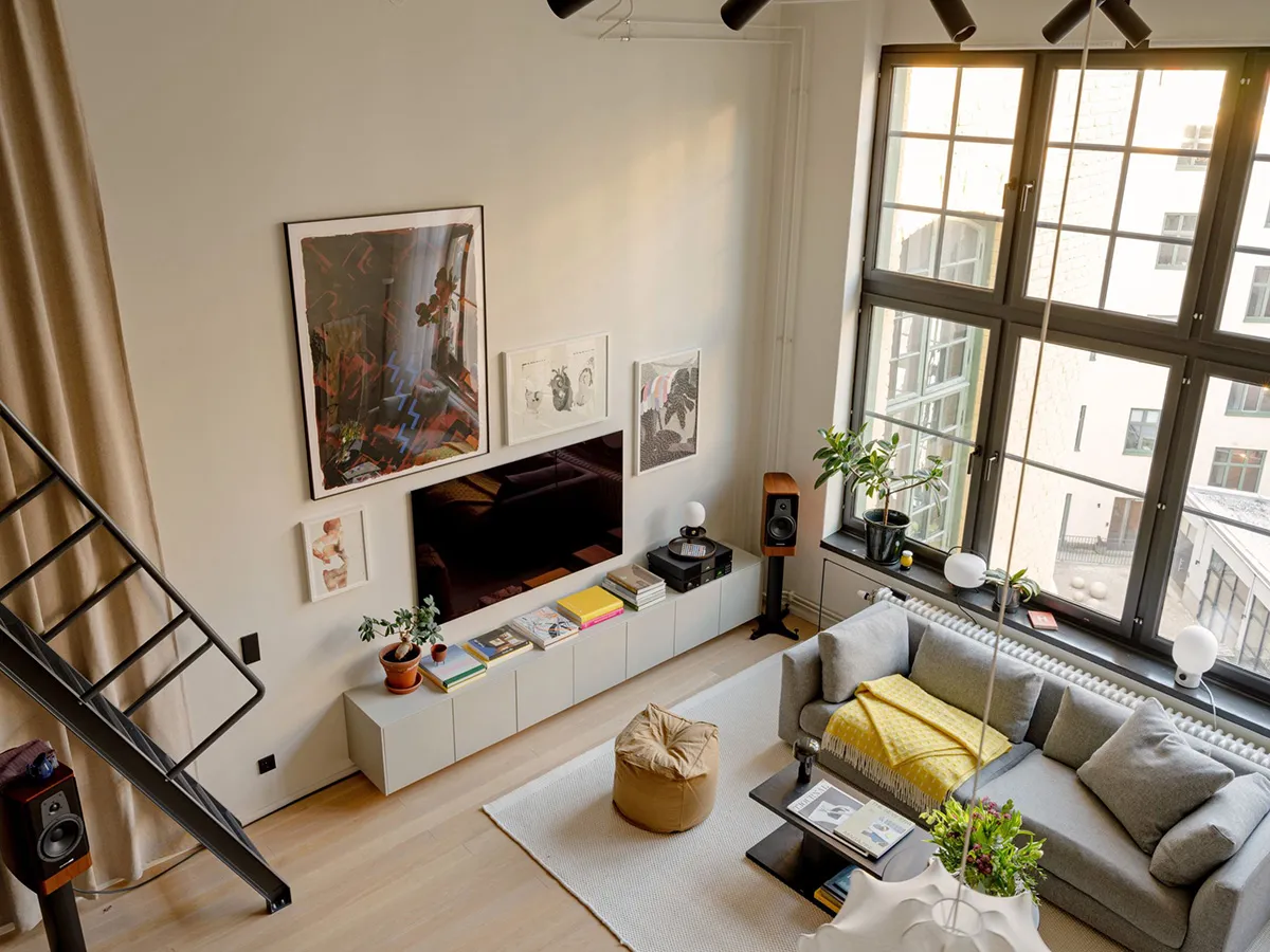 A modern living room with a grey couch, a plant, and a wooden floor.