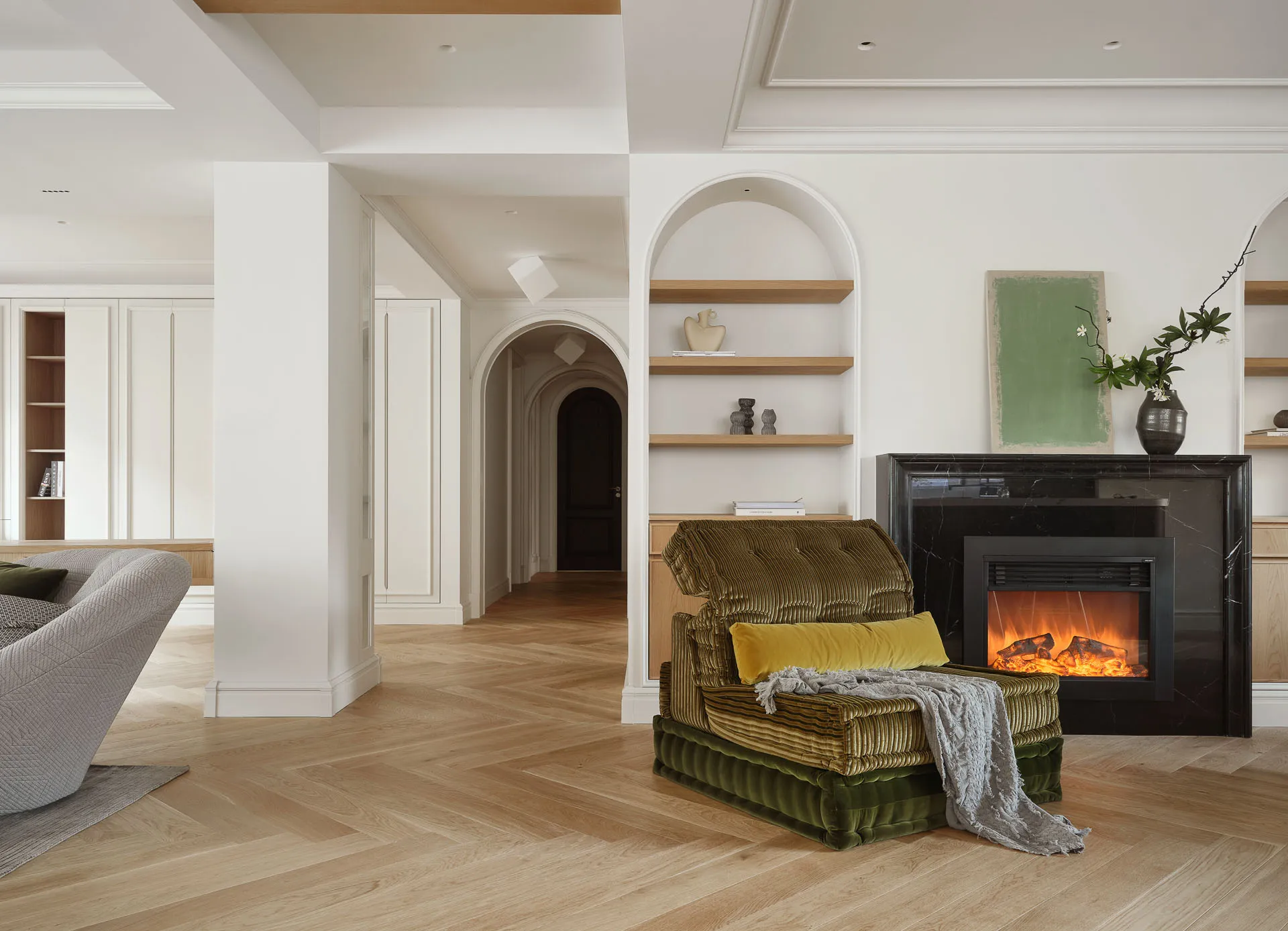 Modern living room featuring wooden flooring and furniture with a cozy fireplace and shelves.