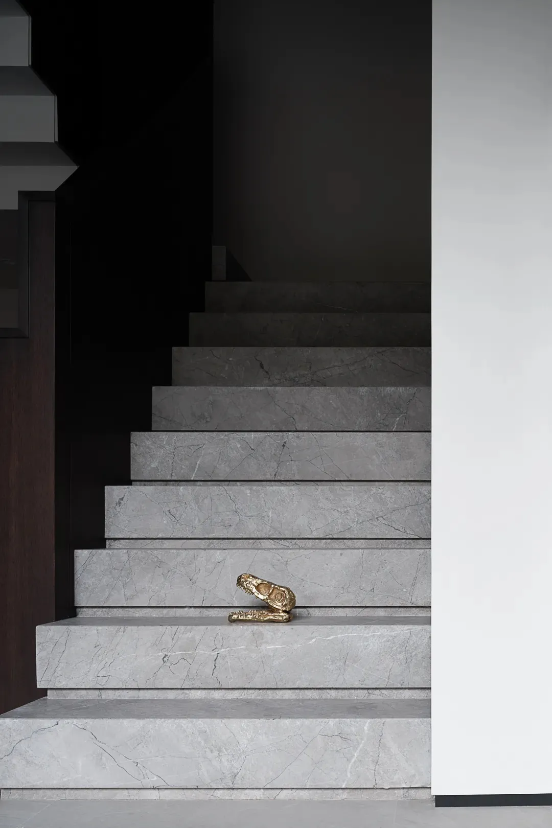 Modern interior space featuring marble stairs and a small golden skull.