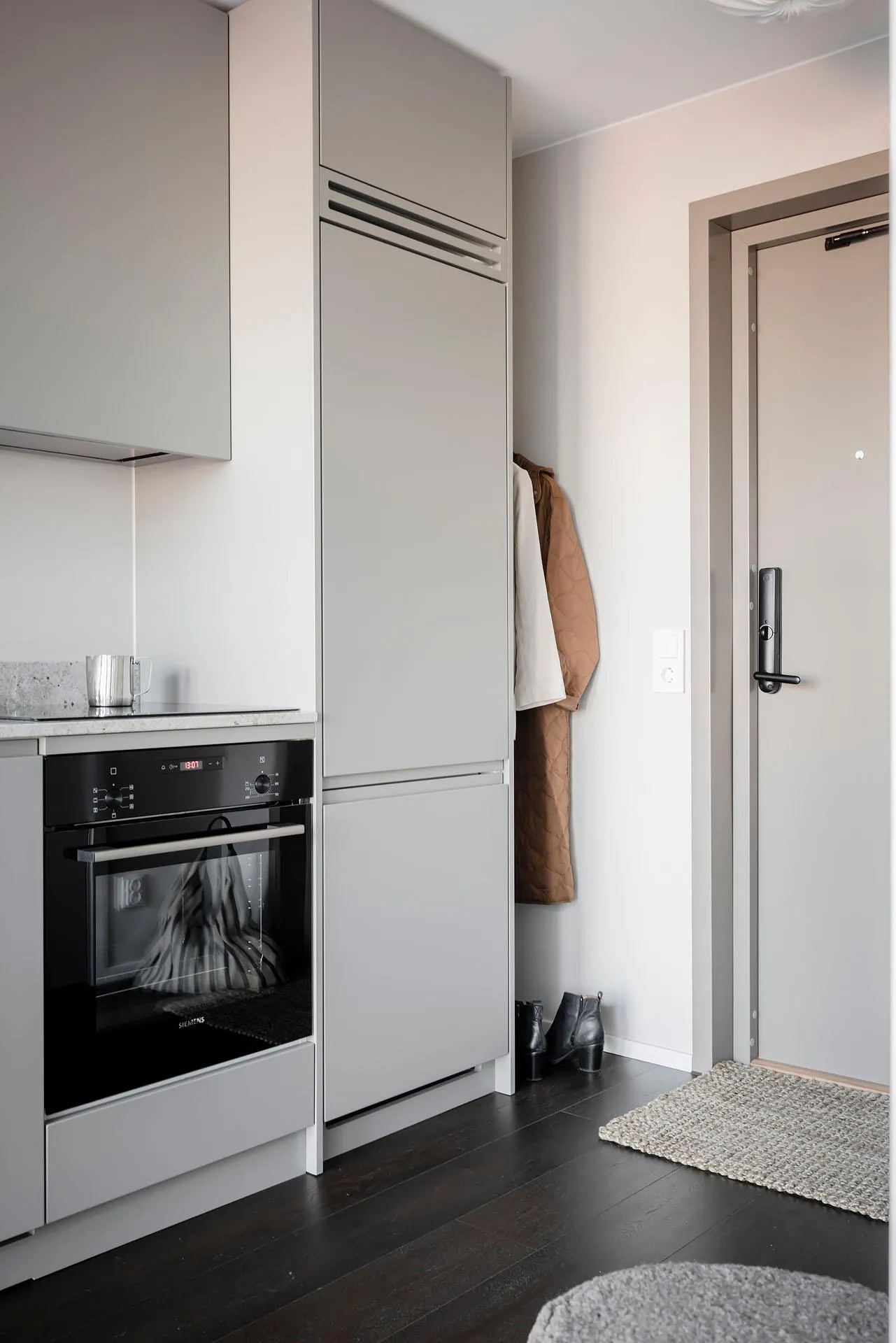 Modern, minimalist kitchen with grey cabinets, black appliances, and neutral decor.