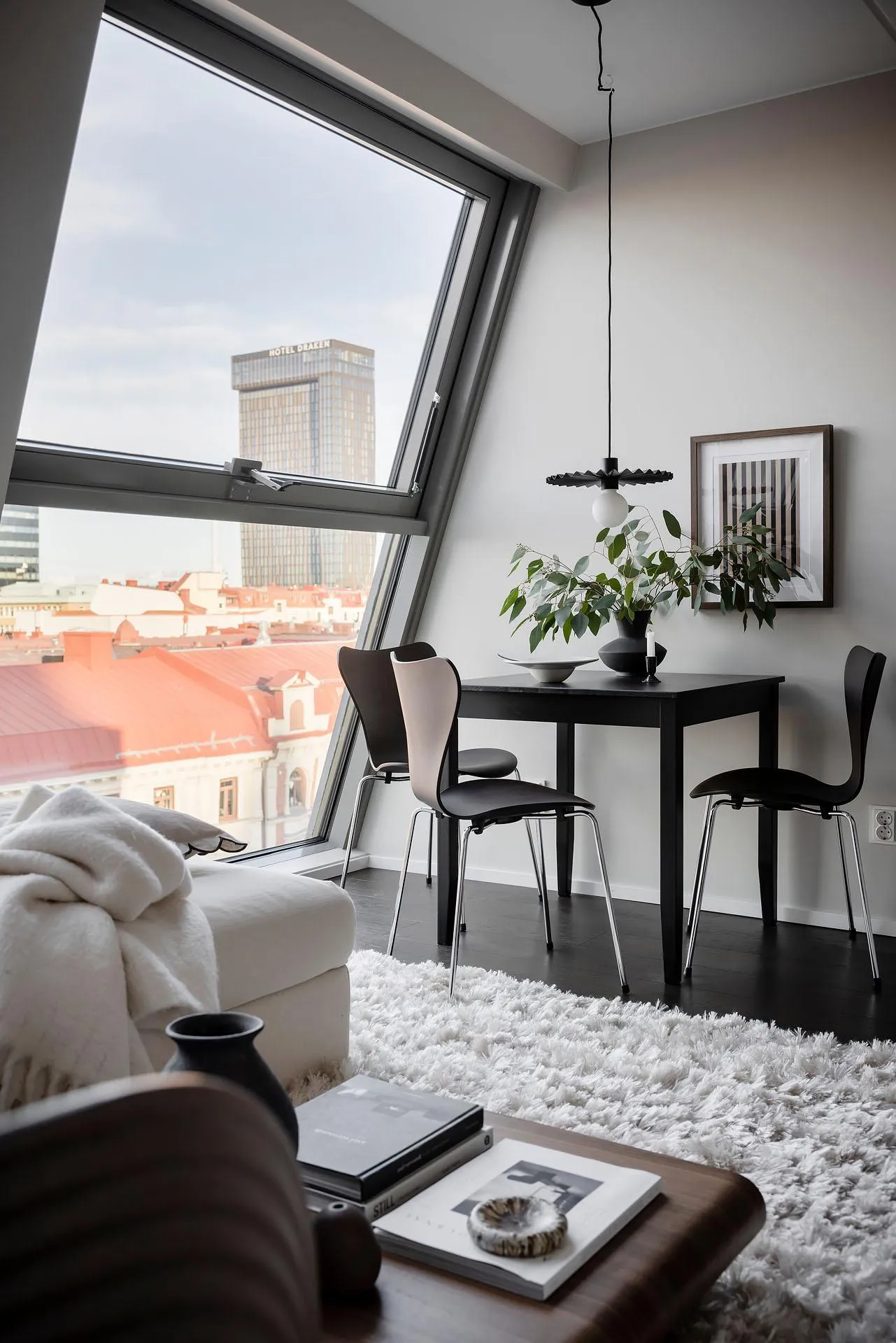 Modern minimalist living room interior with white sofa, black table, and black chairs.