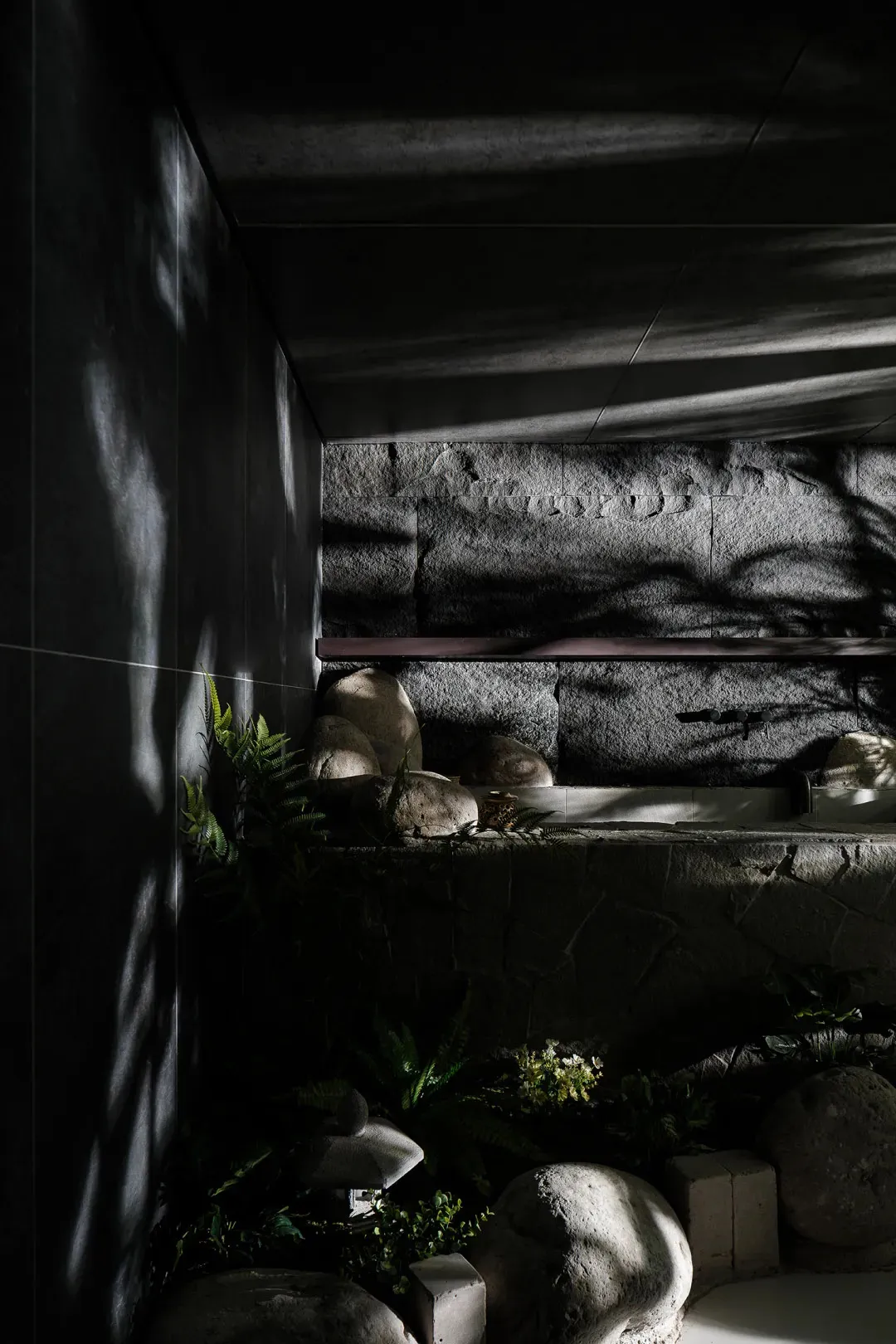 A minimalist concrete bathroom features natural light and rock elements.