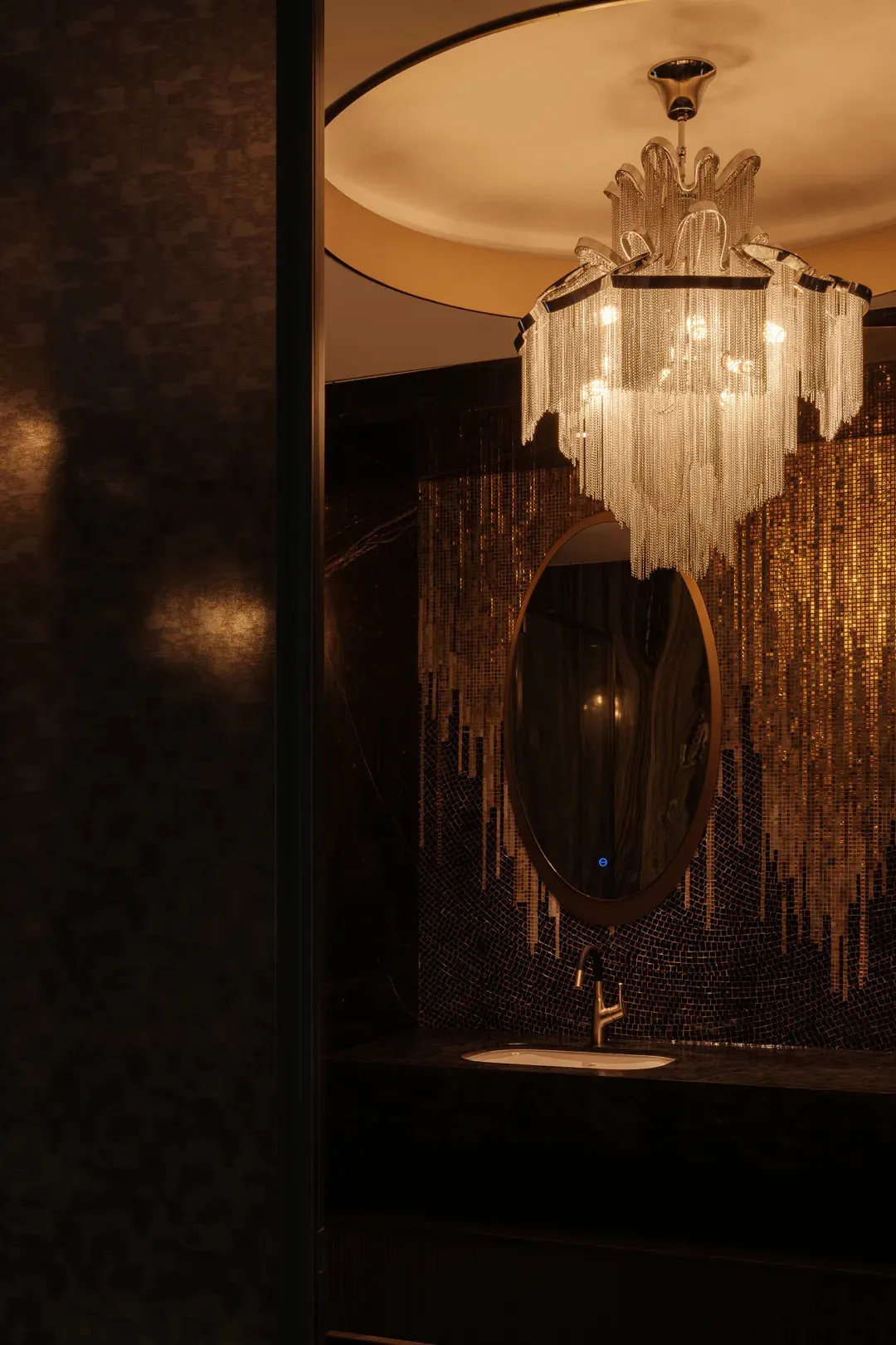 現代浴室配備金屬鏈燈與黑色馬賽克瓷磚牆面。