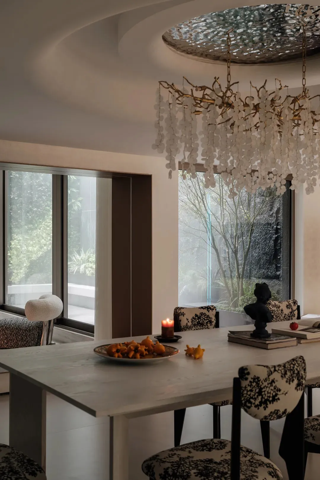 Modern dining room with a white table, chandelier, and chairs with floral upholstery.