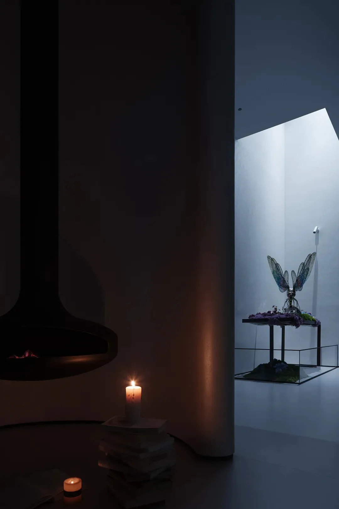 A modern living room featuring a glass window with a fire pit and candle.