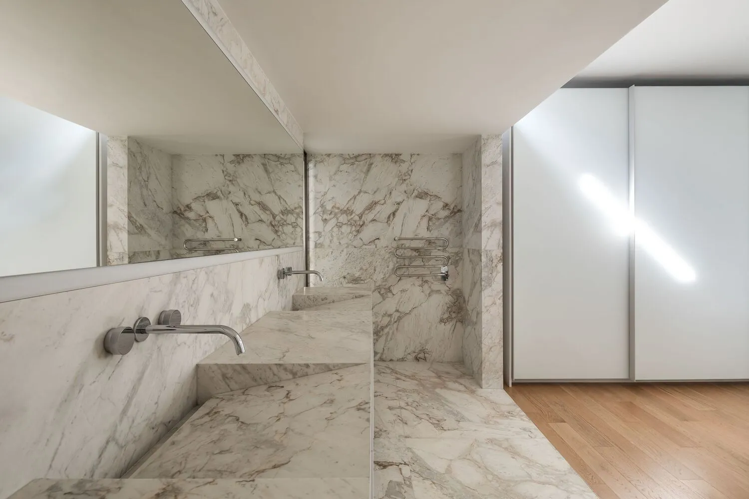 Modern minimalist bathroom with marble walls and floor, featuring sleek, contemporary fixtures.