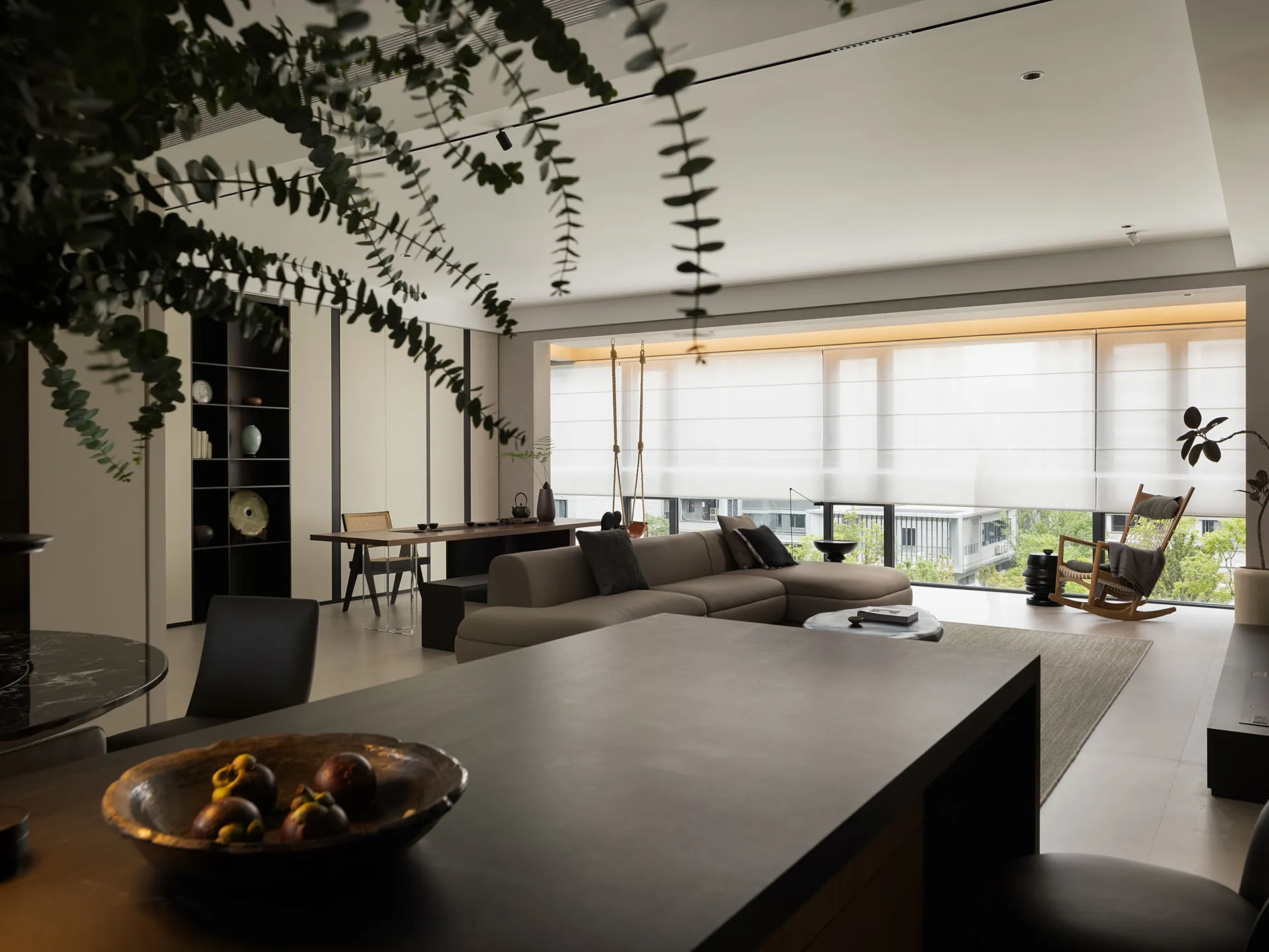 A minimalist living room with neutral furniture and a large window.
