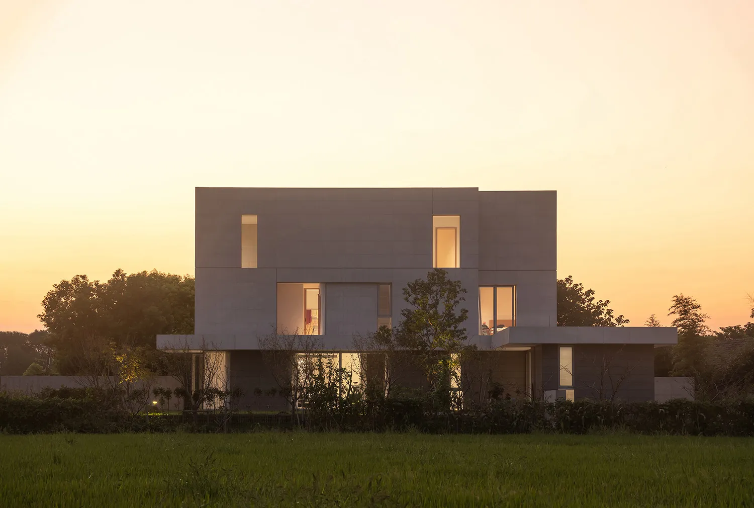 A modern residential home with a concrete exterior and large windows.