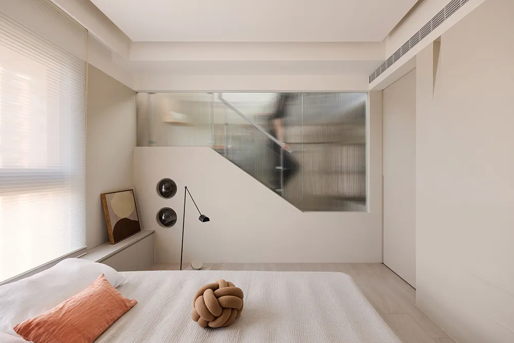 Minimalist bedroom featuring a bed with fabric bedding and a knotted decorative pillow.