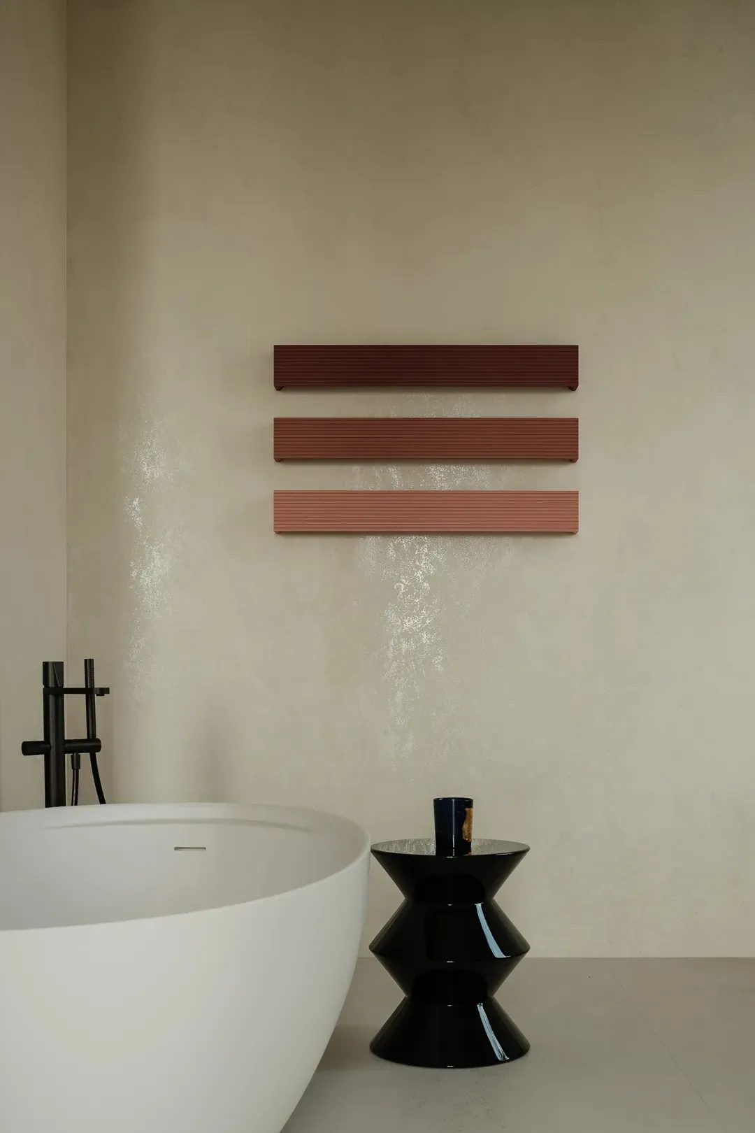 A minimalist bathroom featuring a white bathtub, a black side table, and a wall-mounted concrete shelf with three horizontal