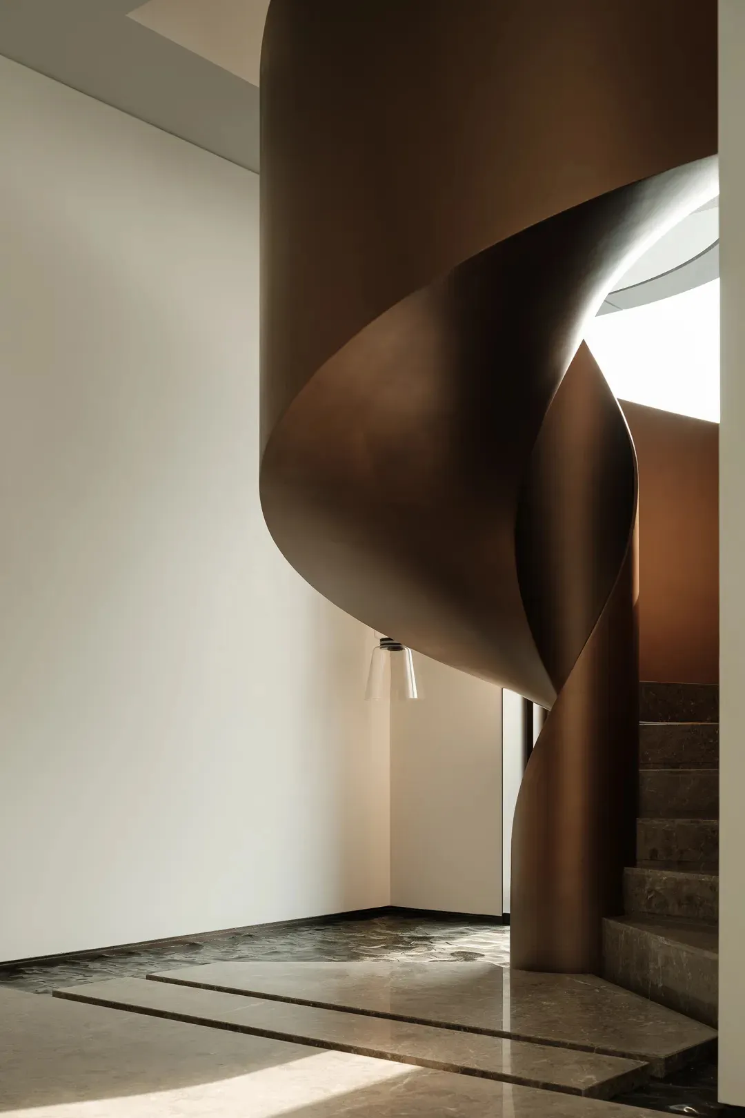 Modern interior featuring a metallic staircase with curved lines and a circular skylight.