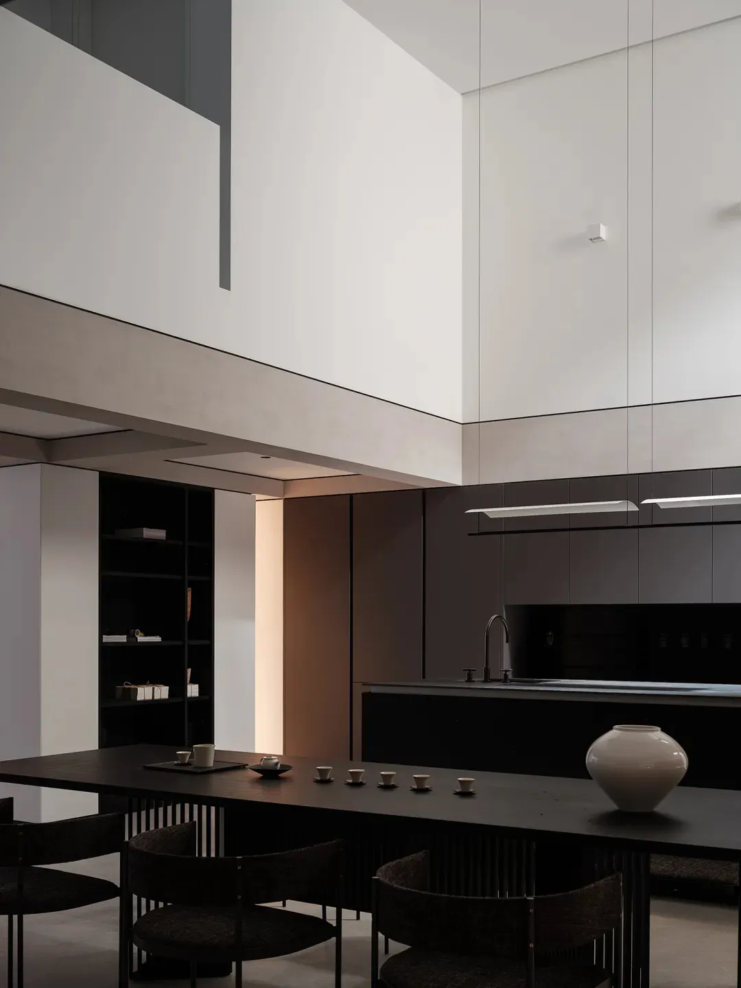 Modern kitchen with black concrete countertops, minimalist design, and high ceilings.