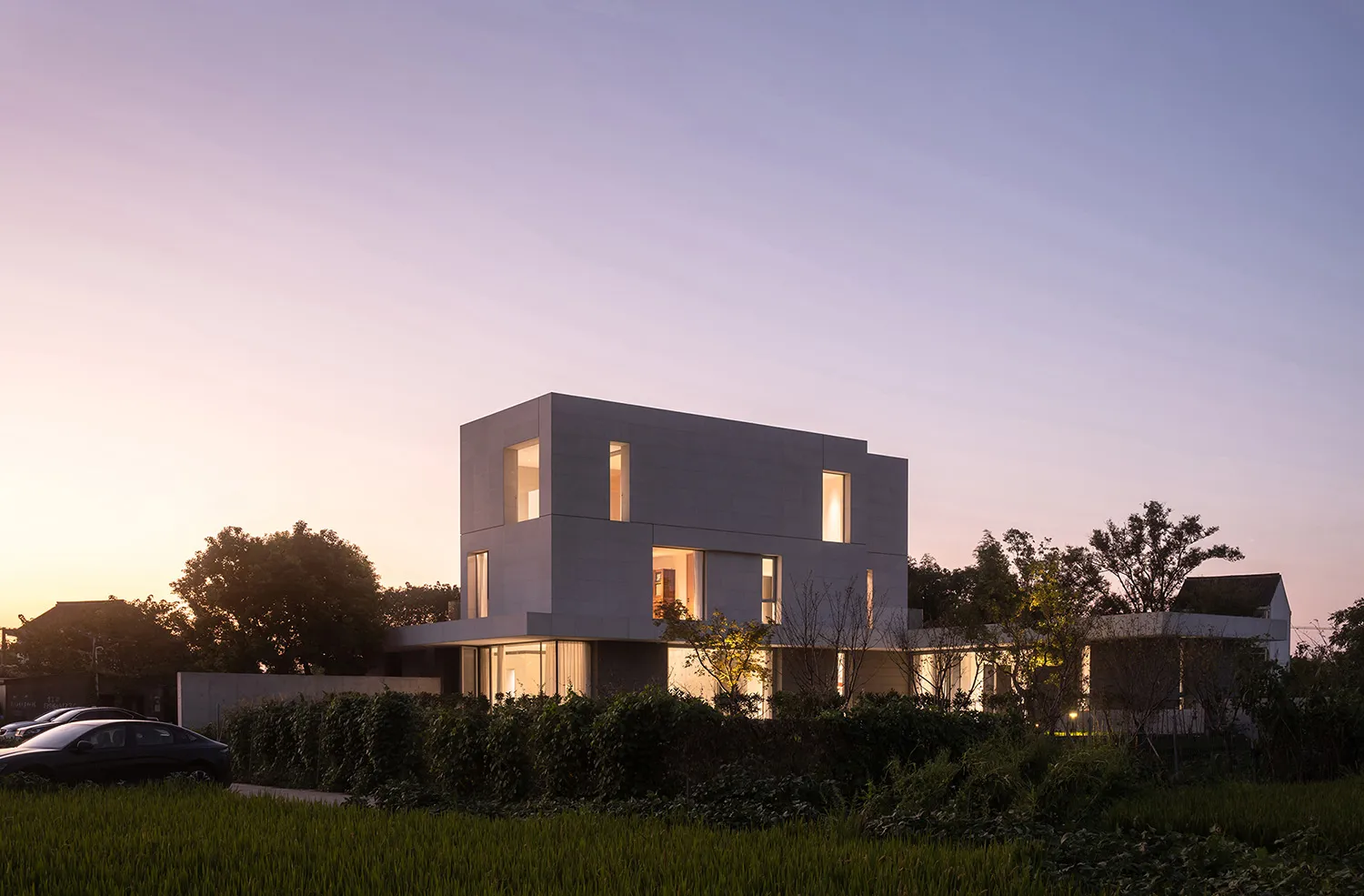Modern minimalist house with concrete and glass exterior at dusk