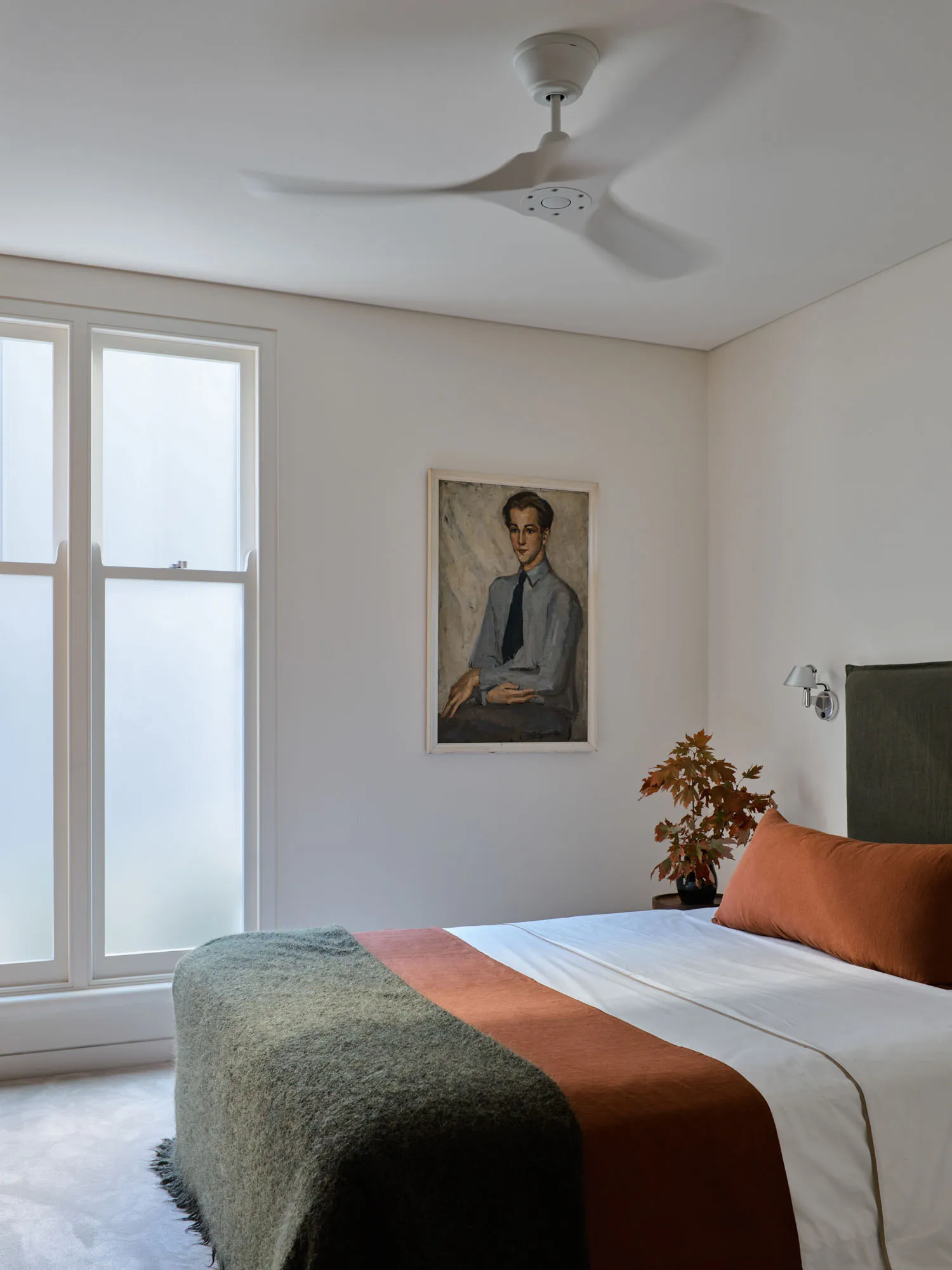 Minimalist bedroom featuring textiles and a potted plant