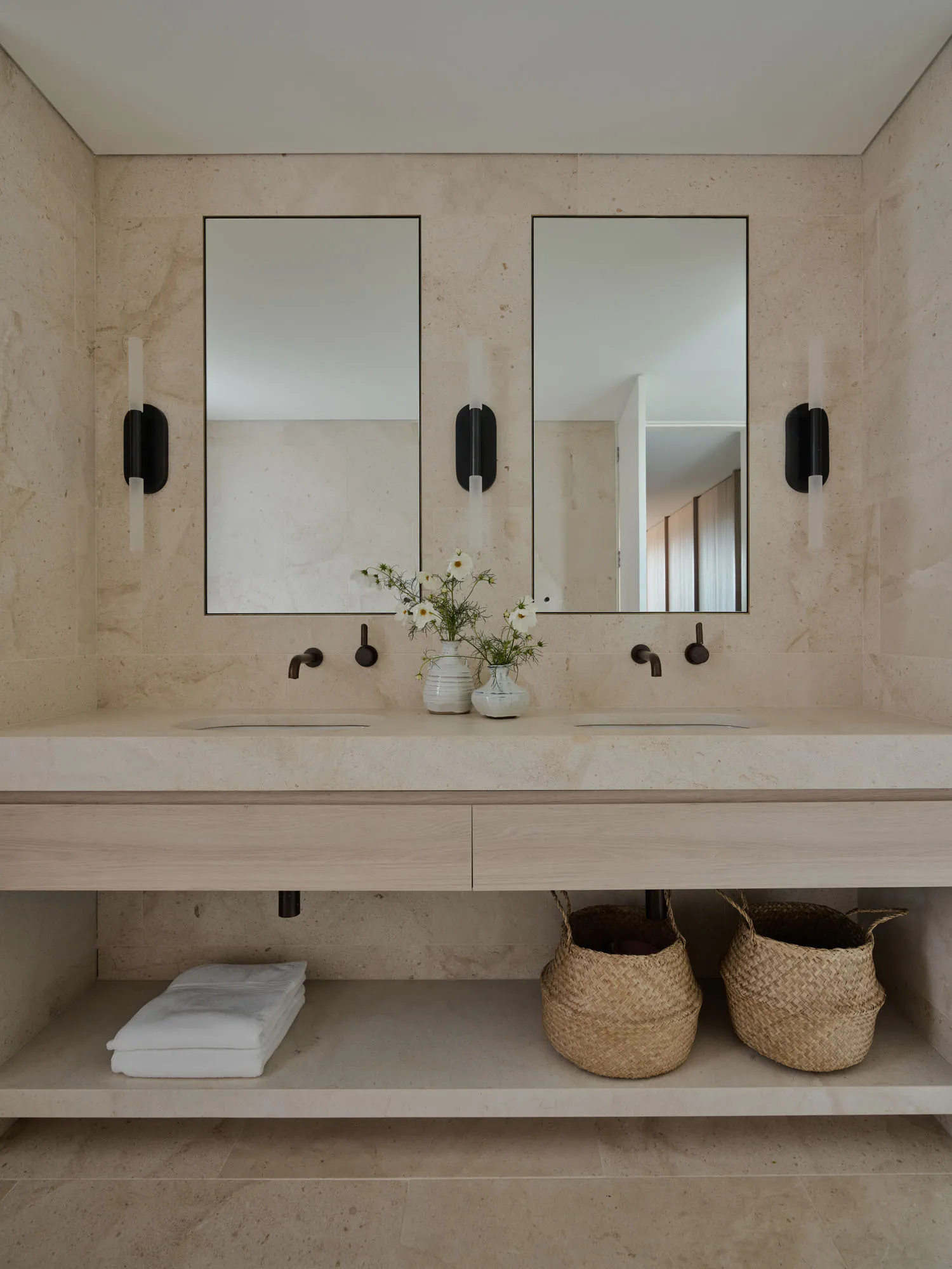 Modern bathroom with marble countertop, sinks, and wall sconces.
