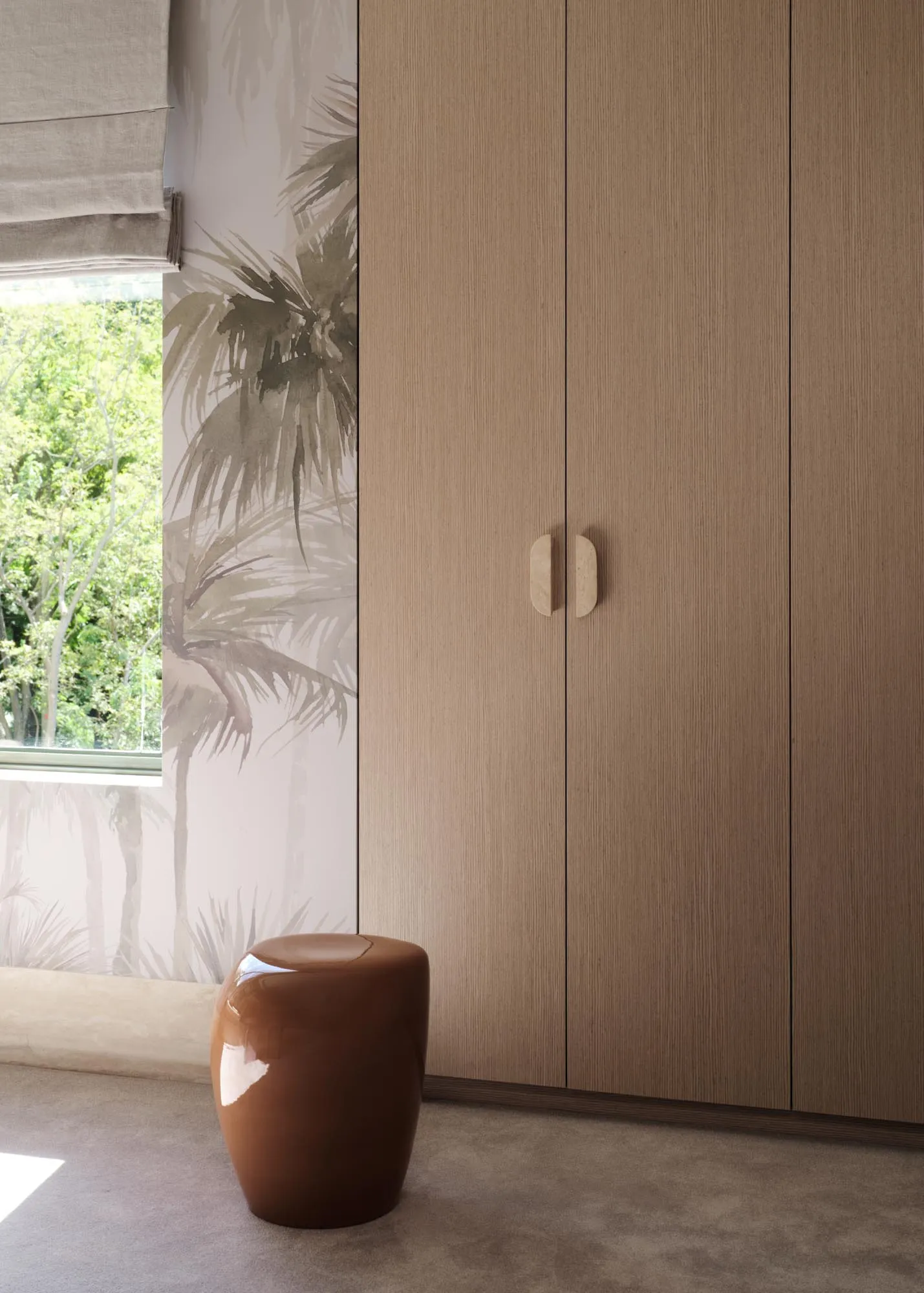 A modern bedroom featuring a wooden cabinet with palm tree wallpaper and a brown ceramic stool.