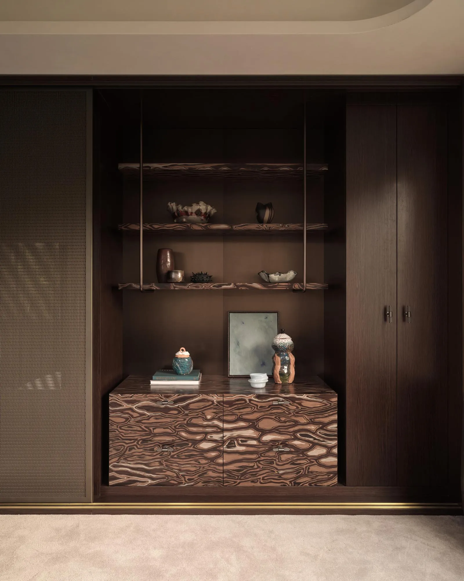 A modern dark wood furniture display with shelves and drawers containing various ceramic objects and books.