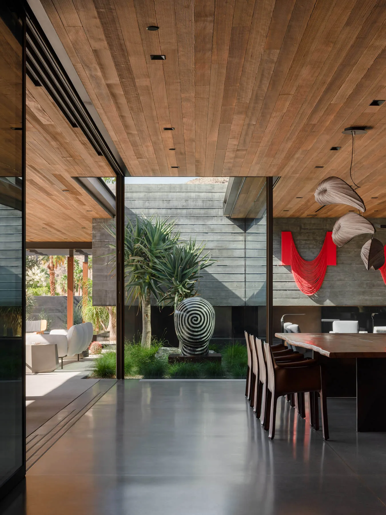 A modern interior space featuring exposed concrete walls and ceiling, floor-to-ceiling glass windows, and illuminated lightin