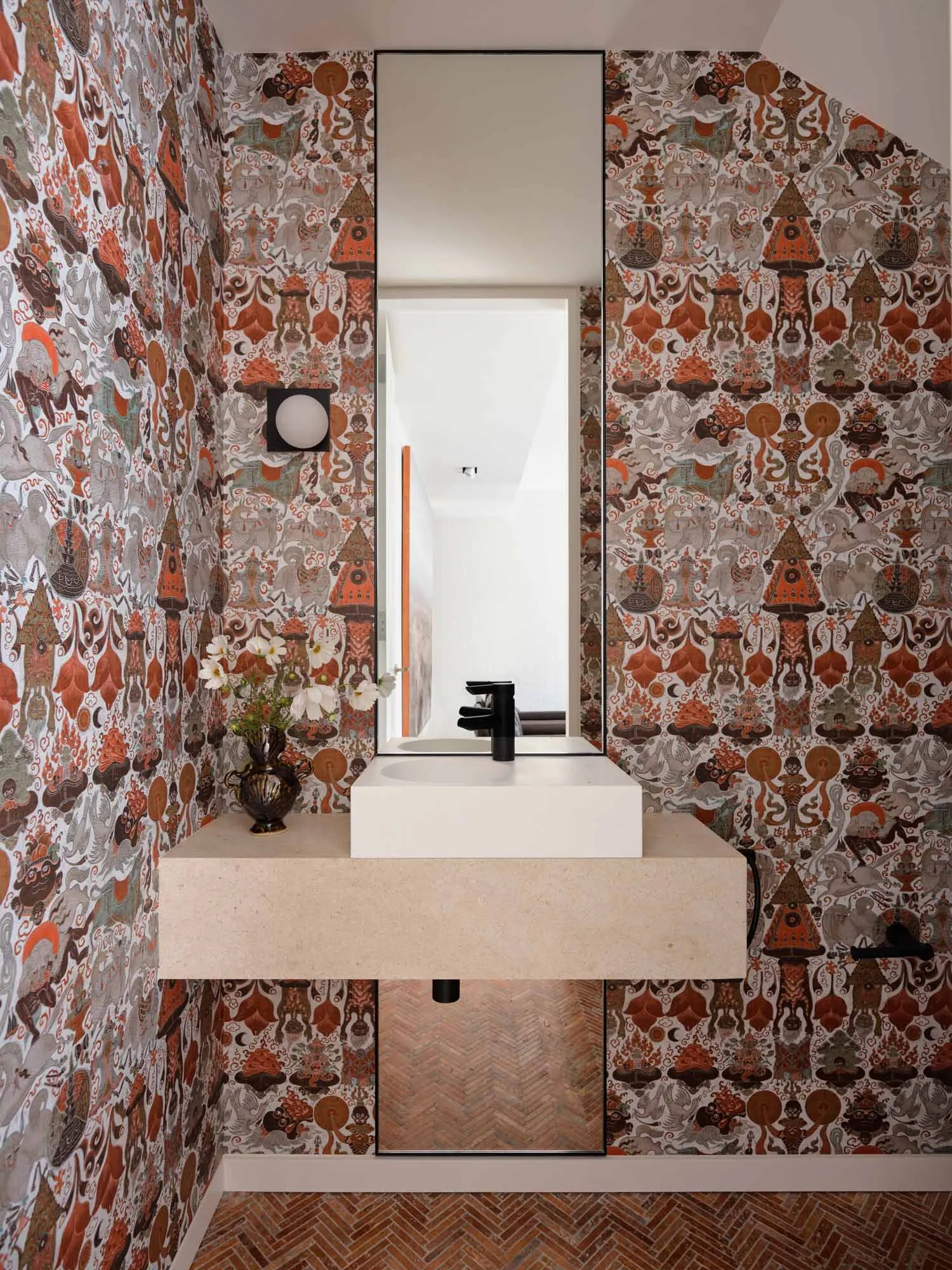 Industrial-style bathroom with tiled walls featuring a pattern of humanoid figures and geometric shapes, complemented by a sl