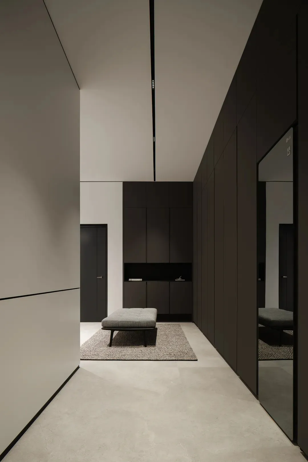 A minimalist closet featuring black wood elements and a large mirror.
