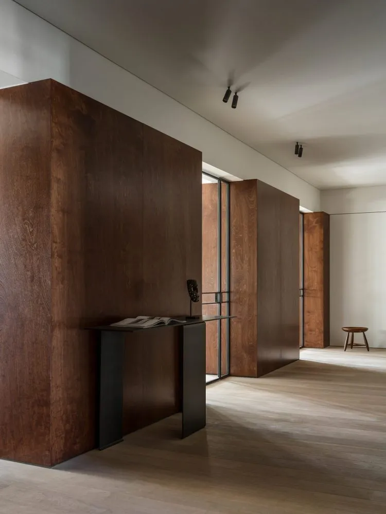 Modern minimalist entrance with dark wooden walls and a sleek black table.