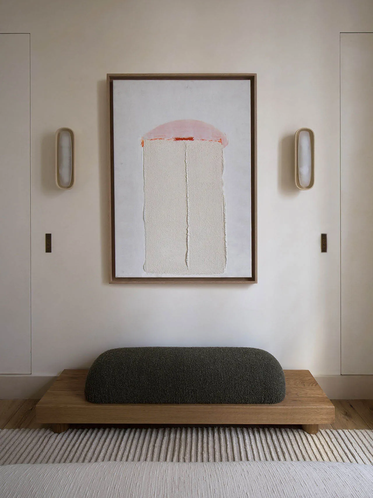 A minimalist interior design with a wooden bench, a wool cushion, and a concrete floor.
